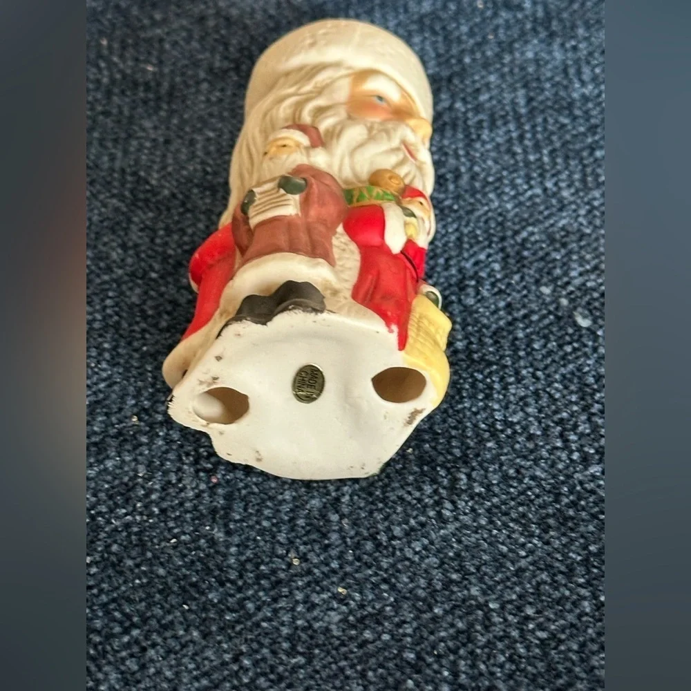 Cute Santa ceramic candleholder. Multiple smaller Santas surrounding the holder.